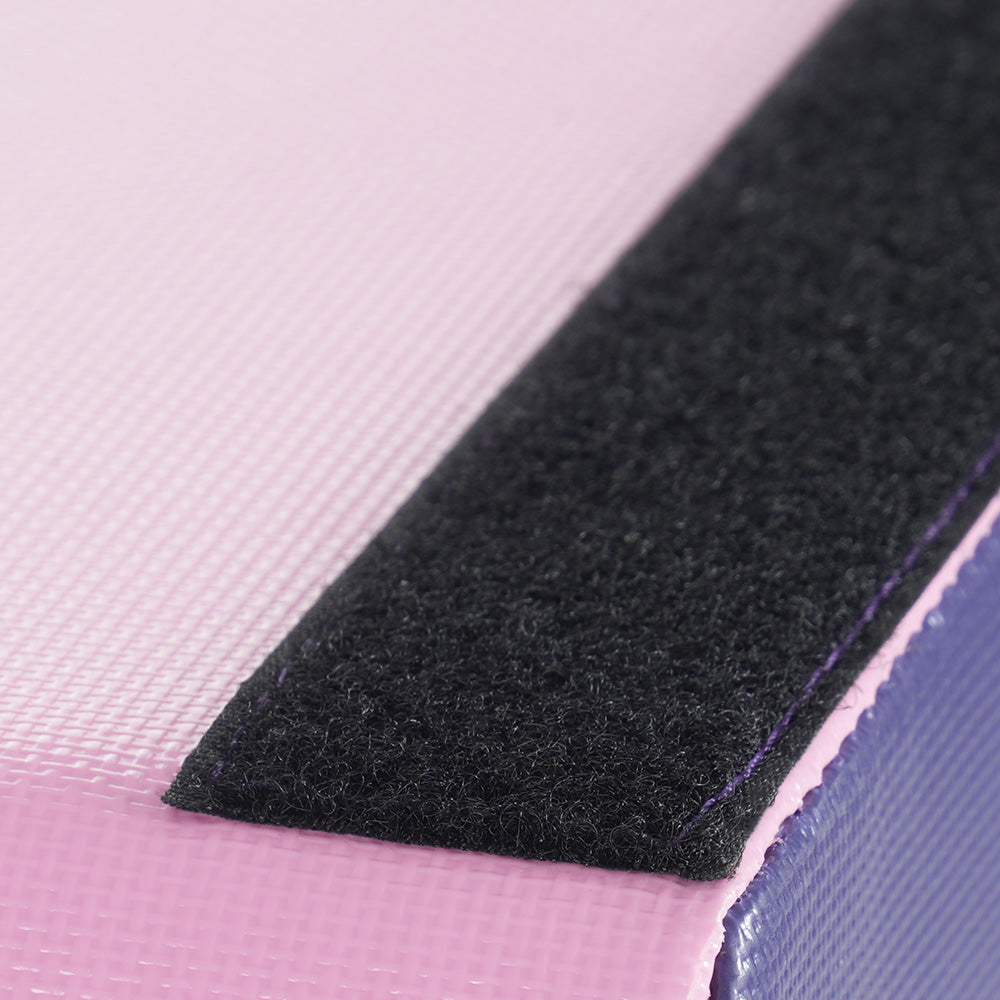 Textured pink exercise mat edge with black velcro strap and purple stitching