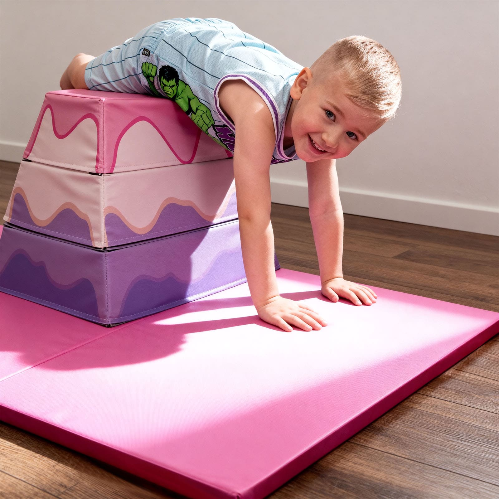 Child playing on pink foam steps and mat indoors
