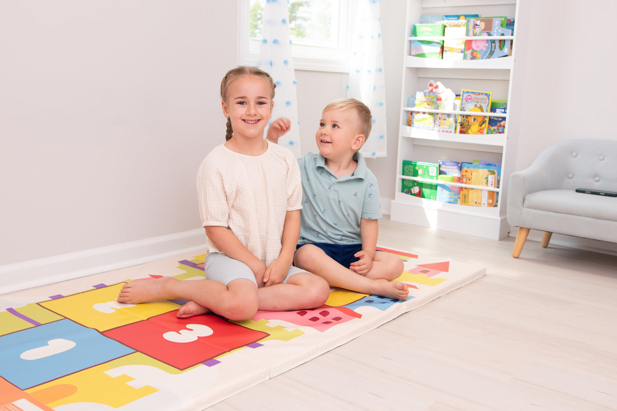 Two children sitting on a colorful gymnastics play mat