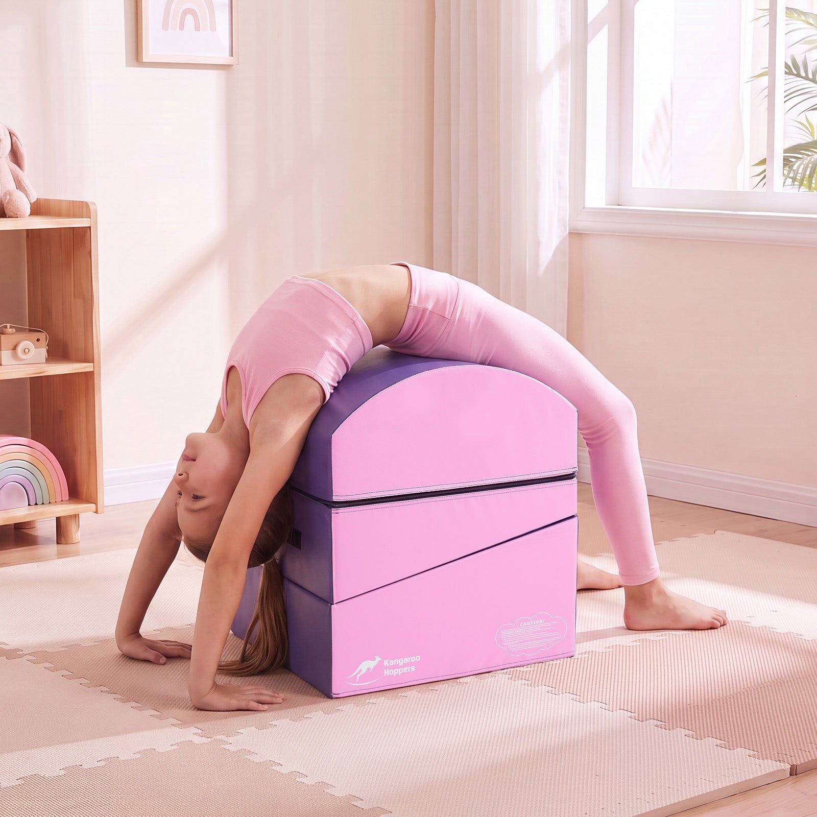 Child performing a backbend stretch using a modular gymnastics trainer at home.